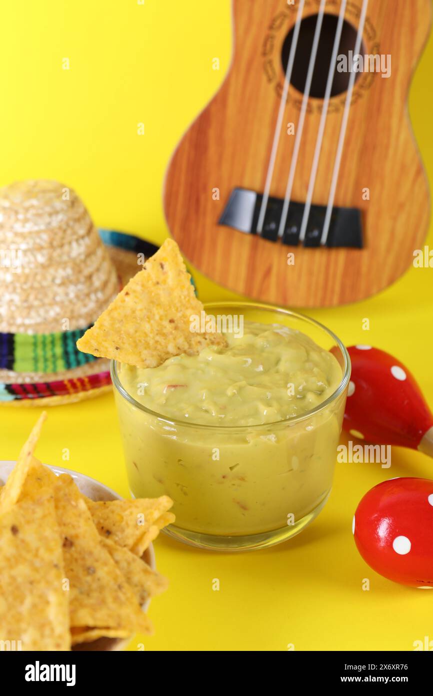 Delicious guacamole with nachos chips, Mexican sombrero hat, ukulele