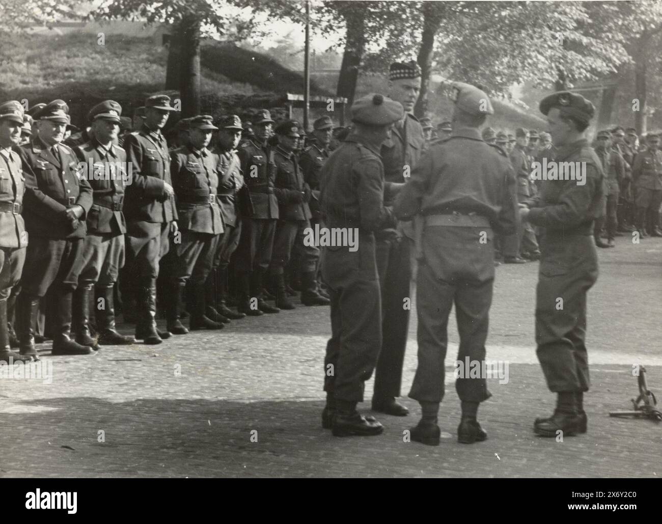 German prisoners of war, German prisoners of war guarded by English? soldiers. In the foreground 4 allied soldiers. At the back of a row are the German prisoners of war., photograph, anonymous, Netherlands, May-1945, photographic support, height, 13 cm × width, 17.5 cm Stock Photo