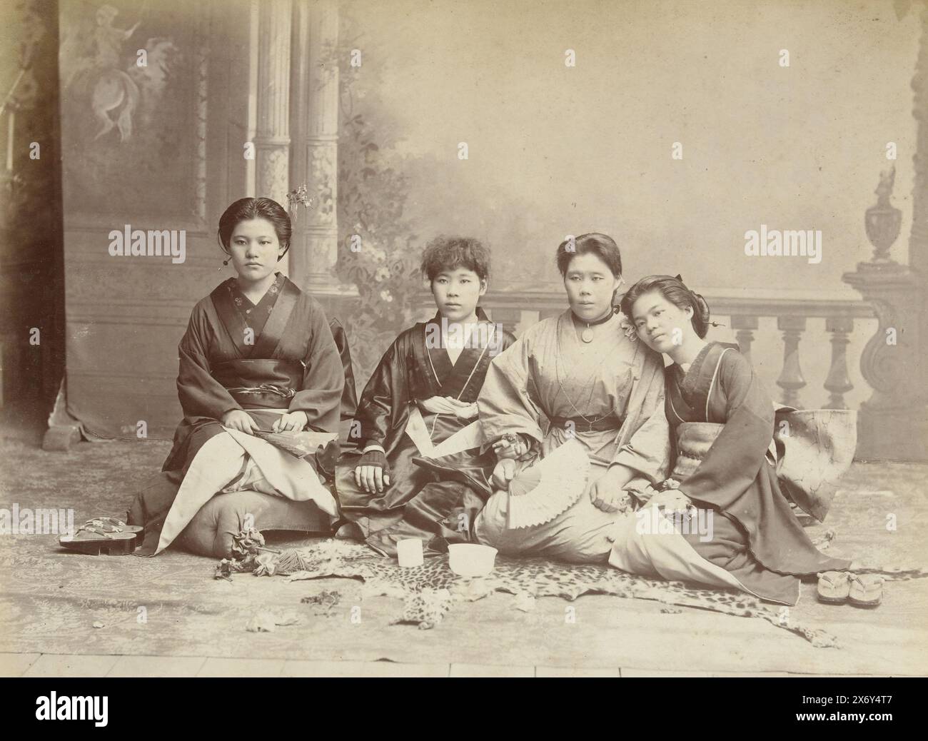 Studio portrait of four Japanese women in kimono, Japanese women, Singapore (title on object), The women wear kimonos and kneel on the ground on a leopard skin. The second lady from the right has a fan in her hand., photograph, anonymous, (mentioned on object), anonymous, (possibly), Singapore, Netherlands, c. 1890 - c. 1910, paper, gelatin silver print, height, 200 mm × width, 280 mm, height, 570 mm × width, 463 mm Stock Photo