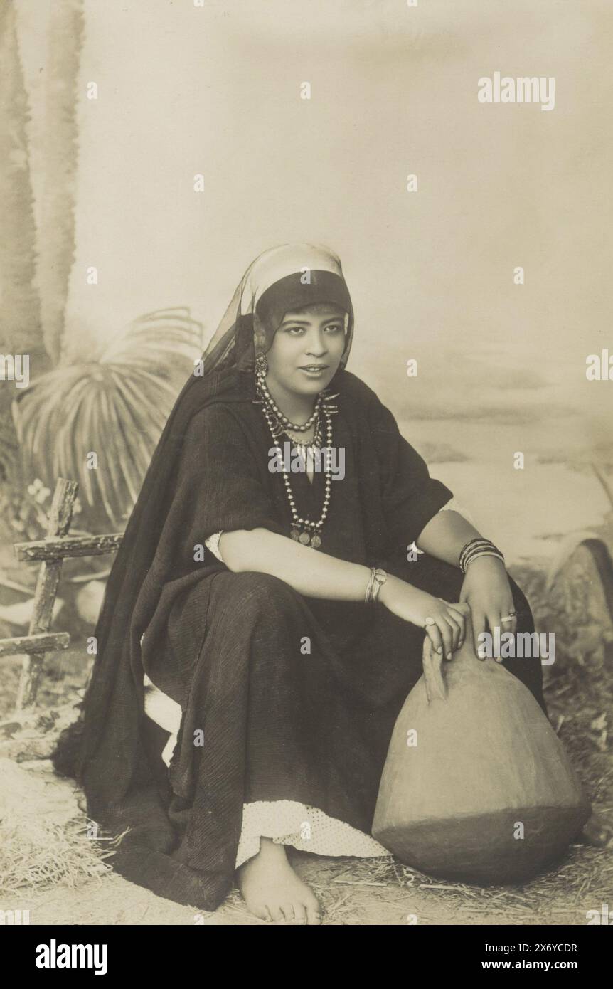 Portrait of an Egyptian woman, crouching with a jug, Femme Egyptienne (title on object), Part of Travel album with photos of sights in Greece and Egypt., photograph, Khardiache Frères, Egypte, c. 1895 - in or before 1905, paper, gelatin silver print, height, 285 mm × width, 189 mm Stock Photo