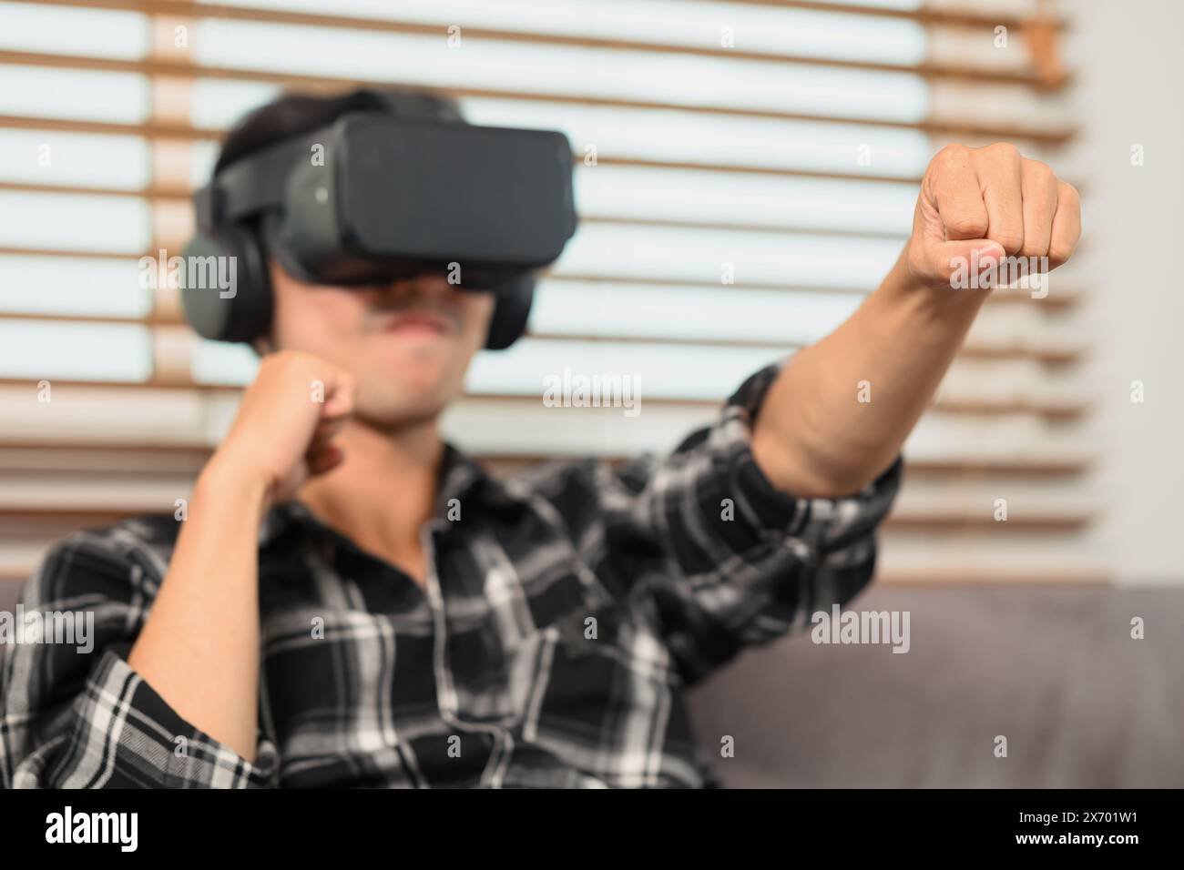 Excited man with VR headset playing boxing game and throwing punches in