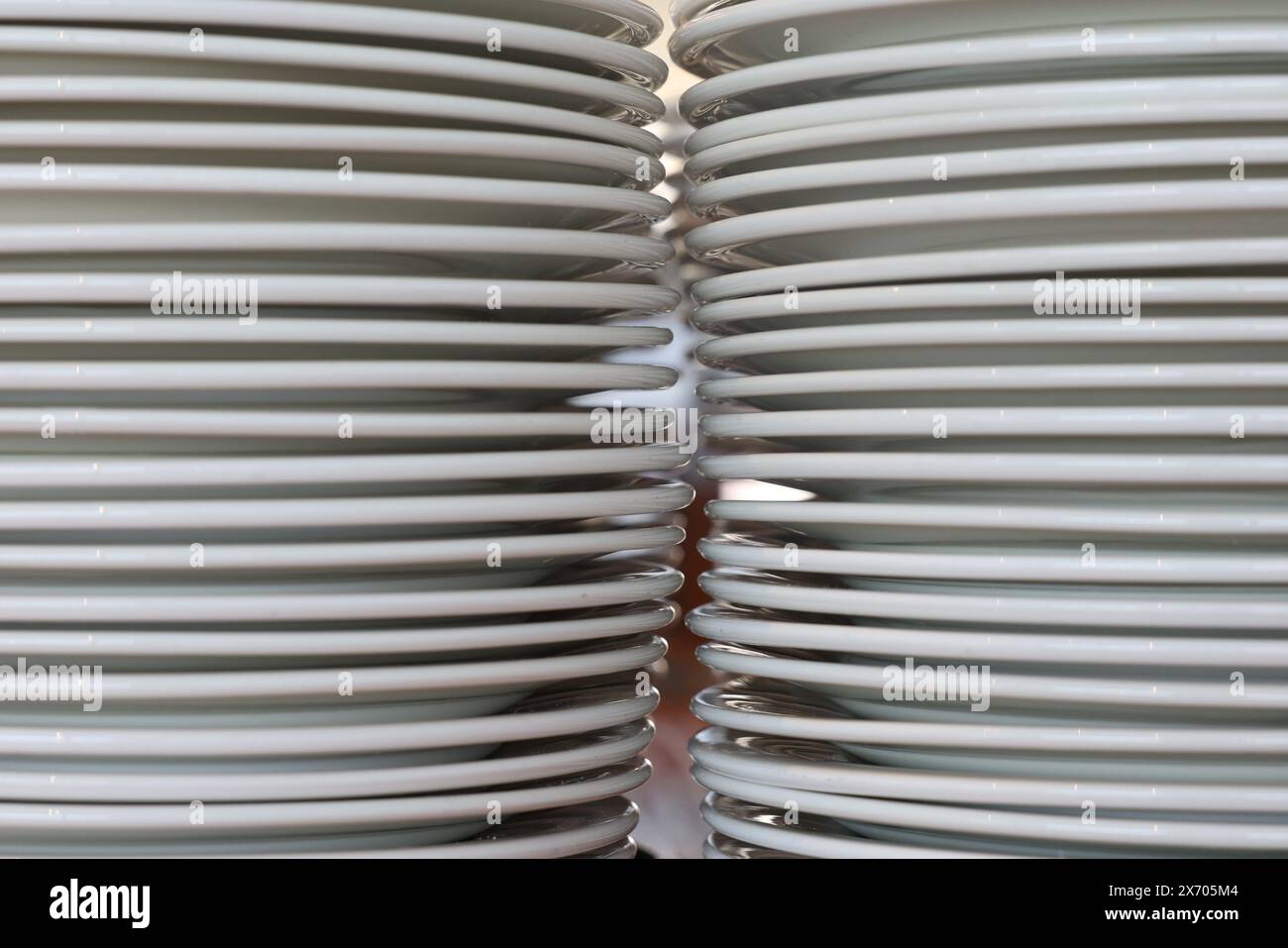 Two stacks of plain white dinner plates photographed up close with a small gap between. Kitchen, function, catering or restaurant concept. Stock Photo