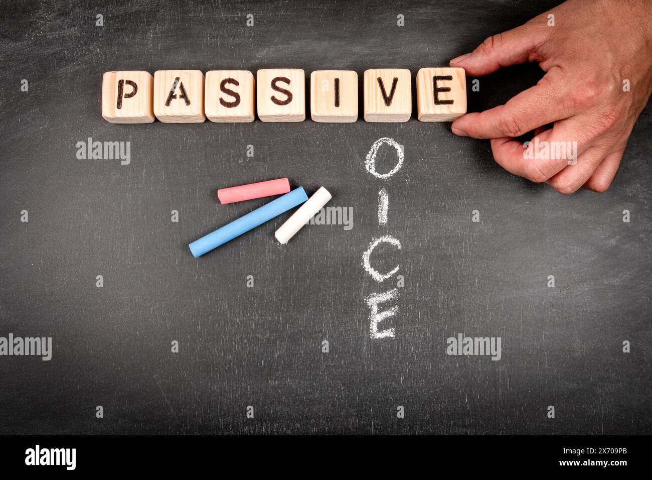 Passive voice. Wooden block crossword puzzle and pieces of chalk on a chalkboard background. Stock Photo