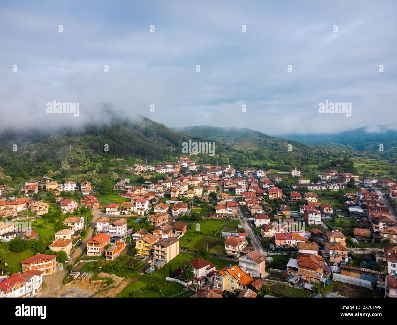 Bulgaria - 05 22 2024: Flying with the Dji mini 2 drone over a village capturing the light hitting the houses with fog coming down from the mountain o Stock Photo