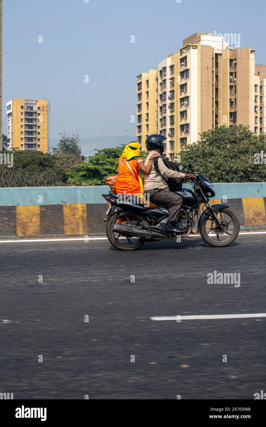 indian couple driving with scooter woman sitting at rear back seat outdoors Stock Photo