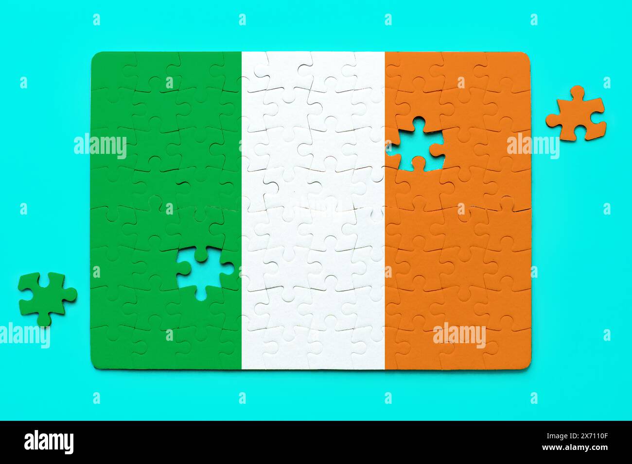 Irish flag puzzle with just two pieces left to complete the image isolated on blue background. Accomplishment and determination related concept. Stock Photo