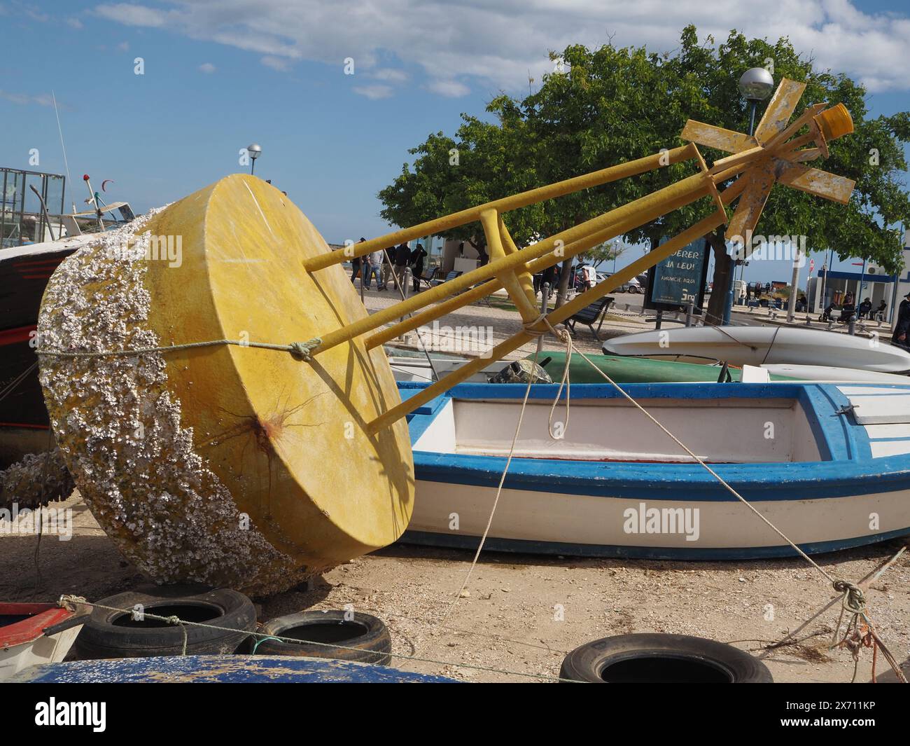 Small pleasure craft with yellow concrete land marker buoy in the foreground in the harbour, Fuseta (Fuzeta), the Algarve southern Portugal. Stock Photo