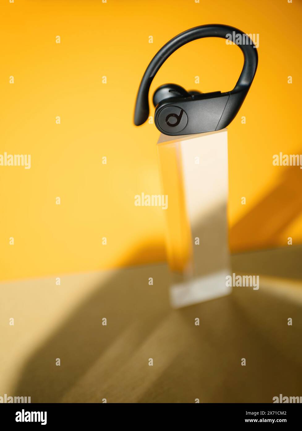London United Kingdom Sep 29 2022 hero objectA close up of a single Powerbeats Pro wireless earbud by Beats showcased on a clear stand against a vibrant orange background emphasizing its design