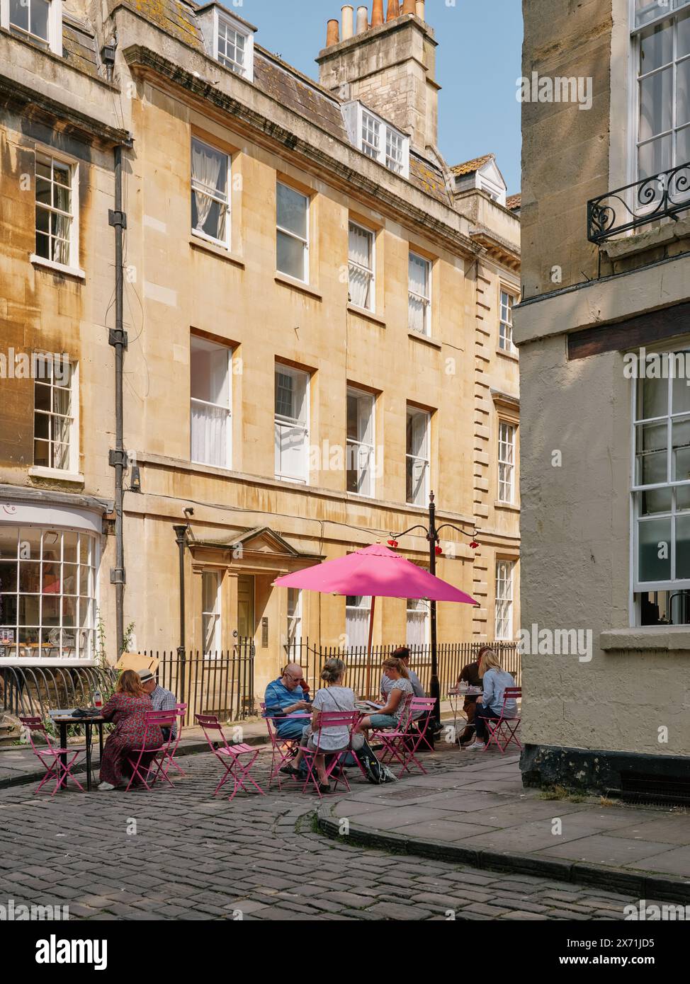 Outdoor cafe tables and summer tourists in a quiet street in Bath ...