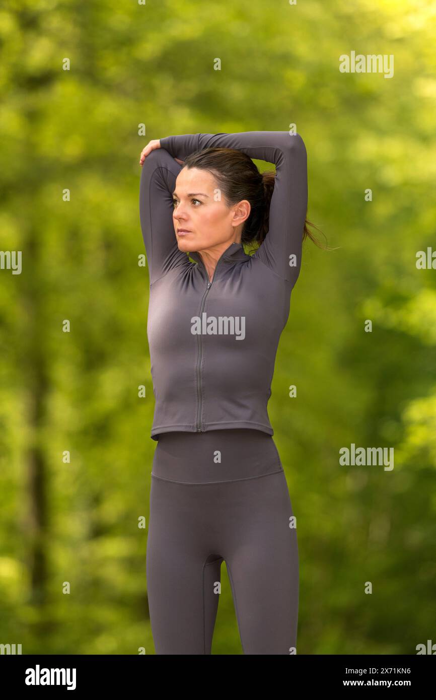 fit woman doing arm stretching exercises in the park Stock Photo