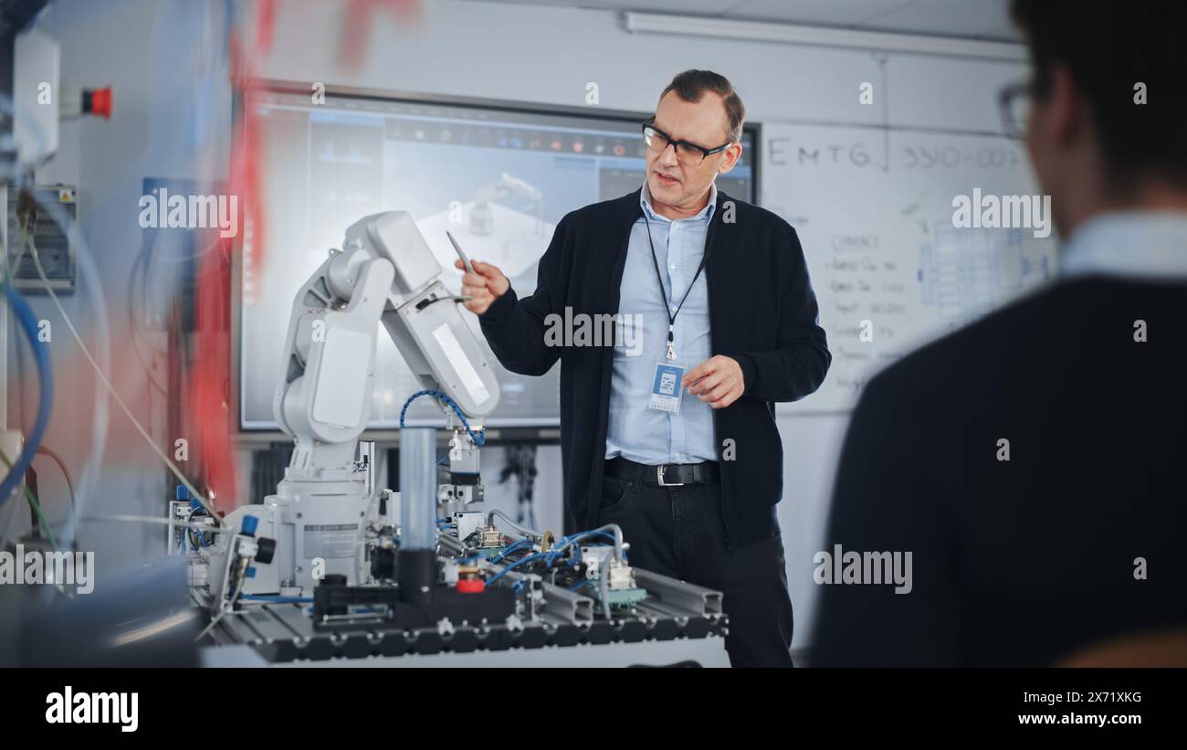 Male Teacher Talking with Students at University Robotics Class at University. Bionic Claw is Moving Under Supervision of the Lector. Computer Science Education and Learning Concept. Stock Photo