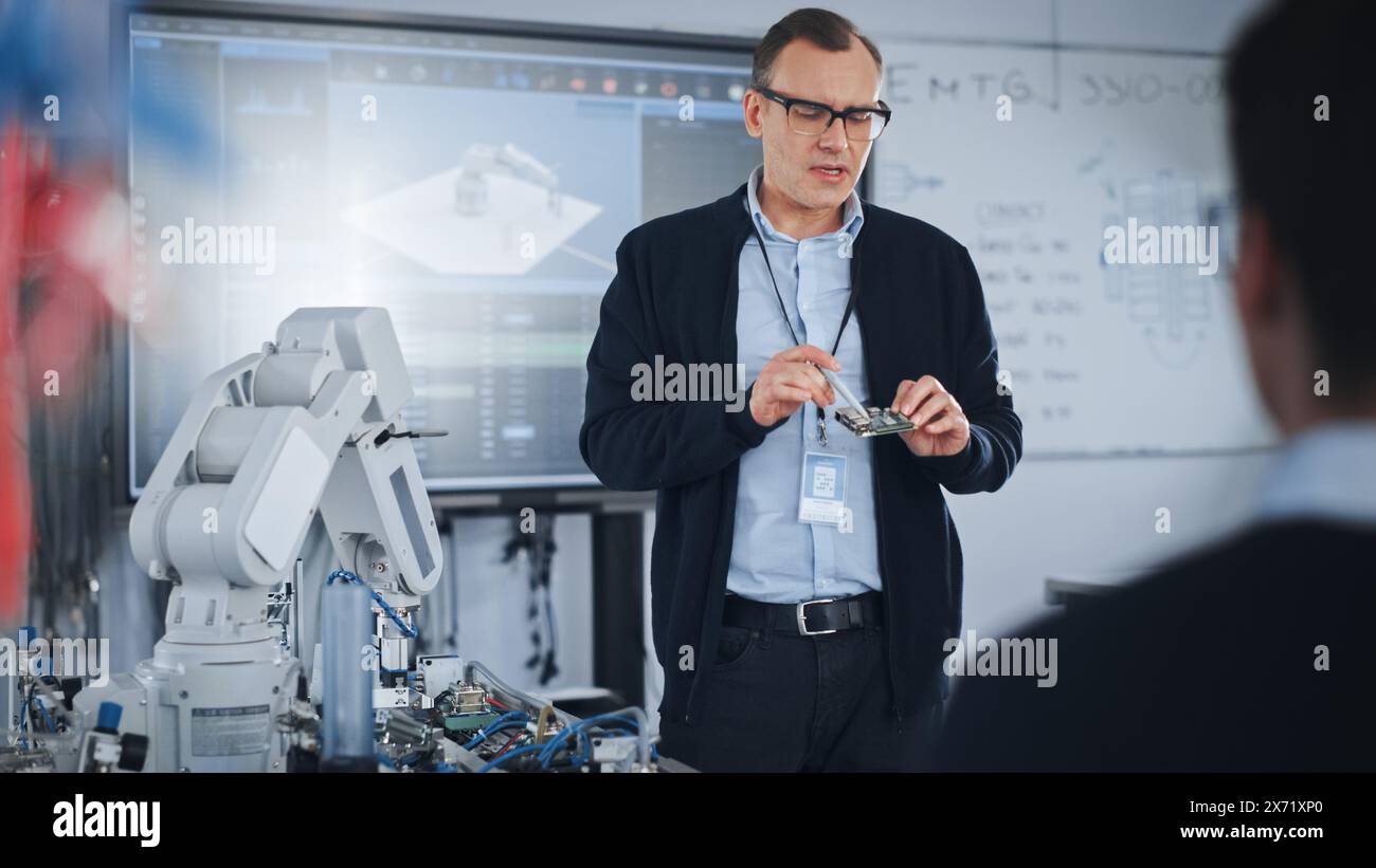 Male Teacher Showing Details and Having Lesson with Students at University Robotics Class at University. Computer Science Education and Machine Learning. Robot Arm Concept. Stock Photo