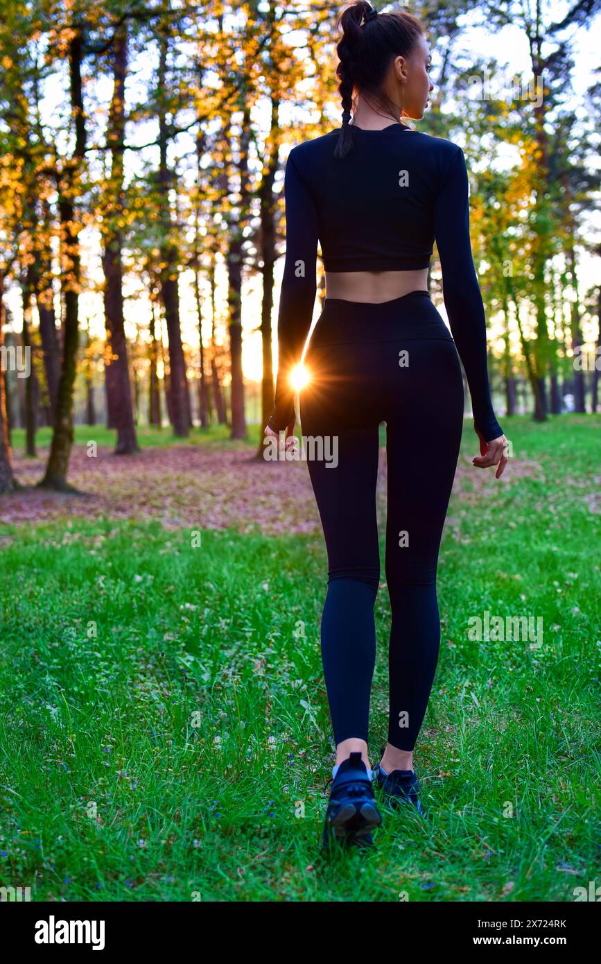 Shapely woman in black tight suit walking in nature in the woods in the sunlight. spring,summer Stock Photo