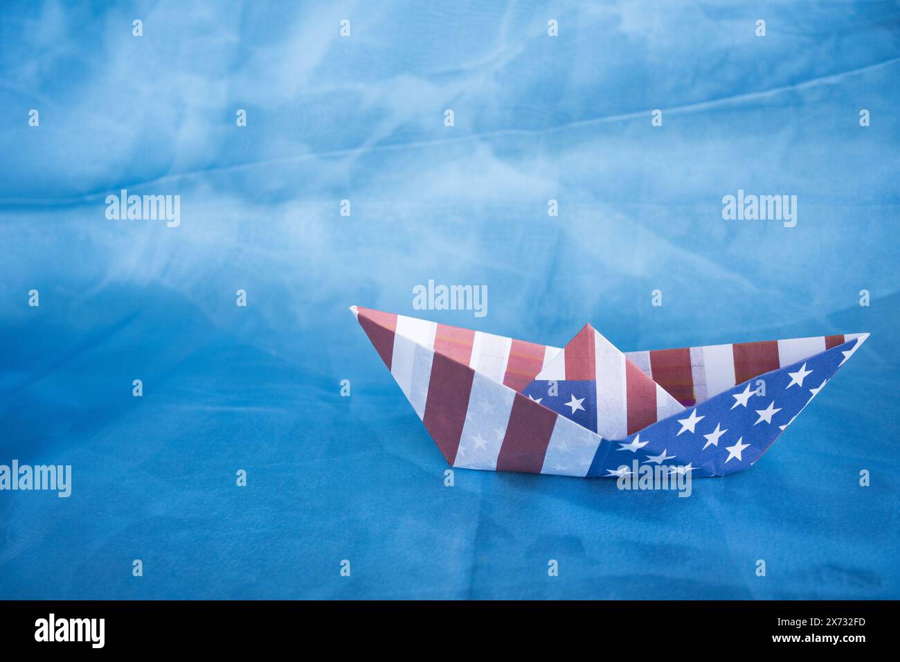 Paper boat with American flag on blue background.  Columbus day concept. Stock Photo