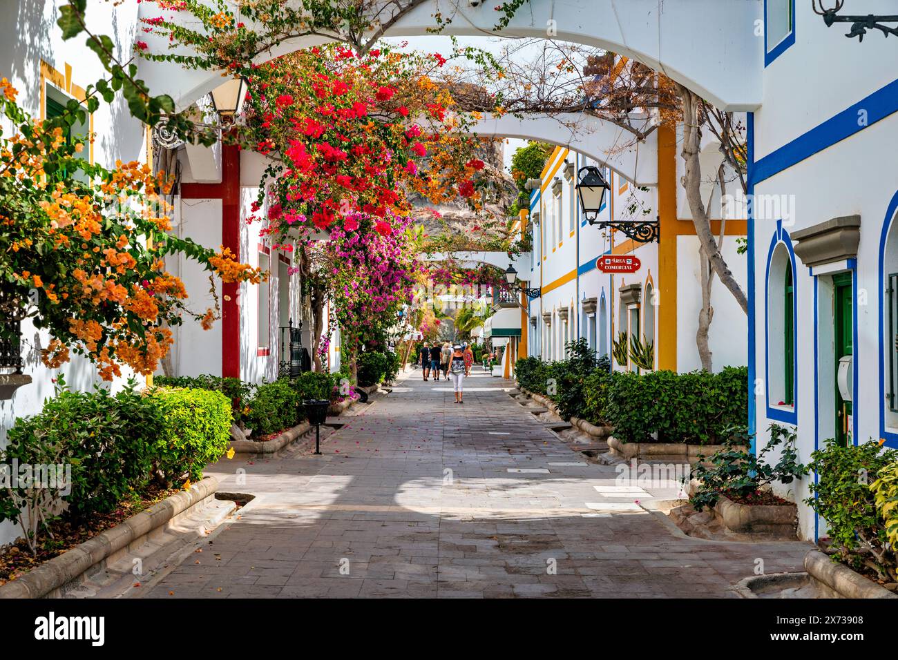 Street with blooming flowers in Puerto de Mogan, Gran Canaria, Spain. Favorite vacation place for tourists and locals on island. Puerto de Mogan with Stock Photo