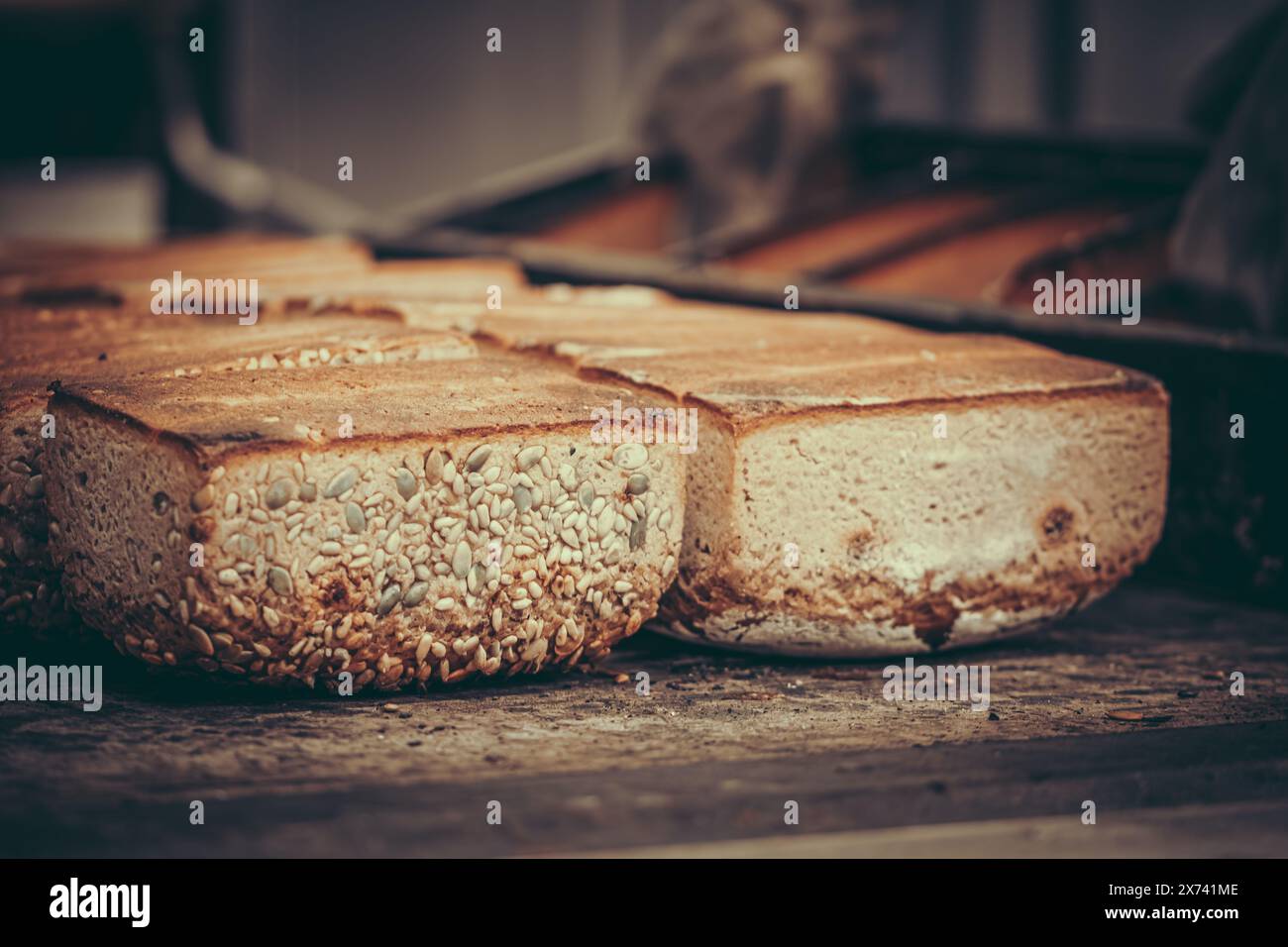 Freshly baked loaves of bread were tipped out of the baking pan upside down onto the wooden table of a bakery. Stock Photo