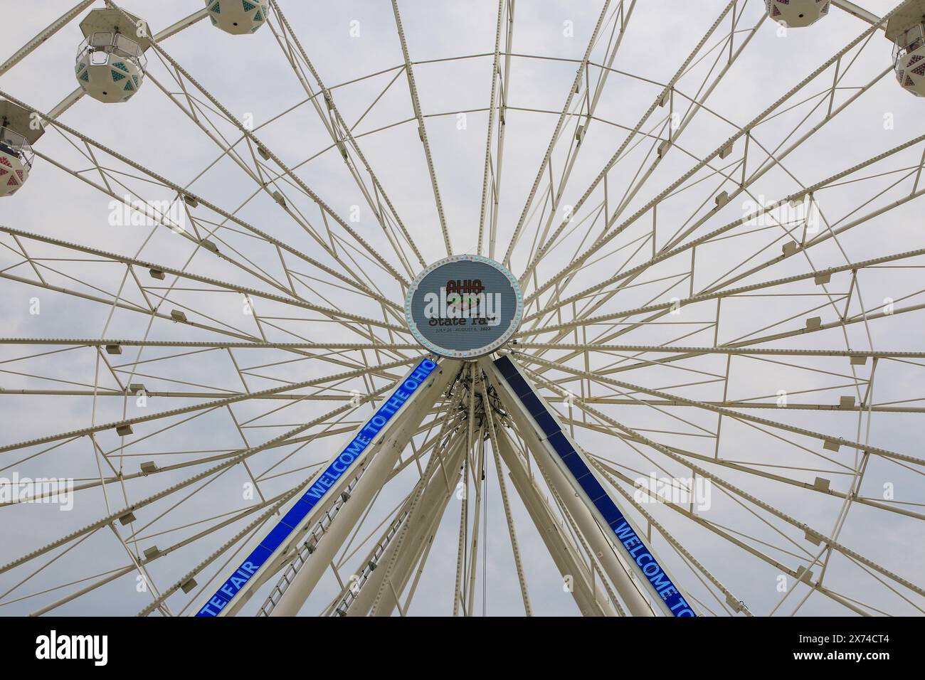 Columbus, Ohio, USA - 5 August 2023: A large white ferris wheel stands tall against the cloudy sky, with empty passenger cabins hanging down at the Oh Stock Photo