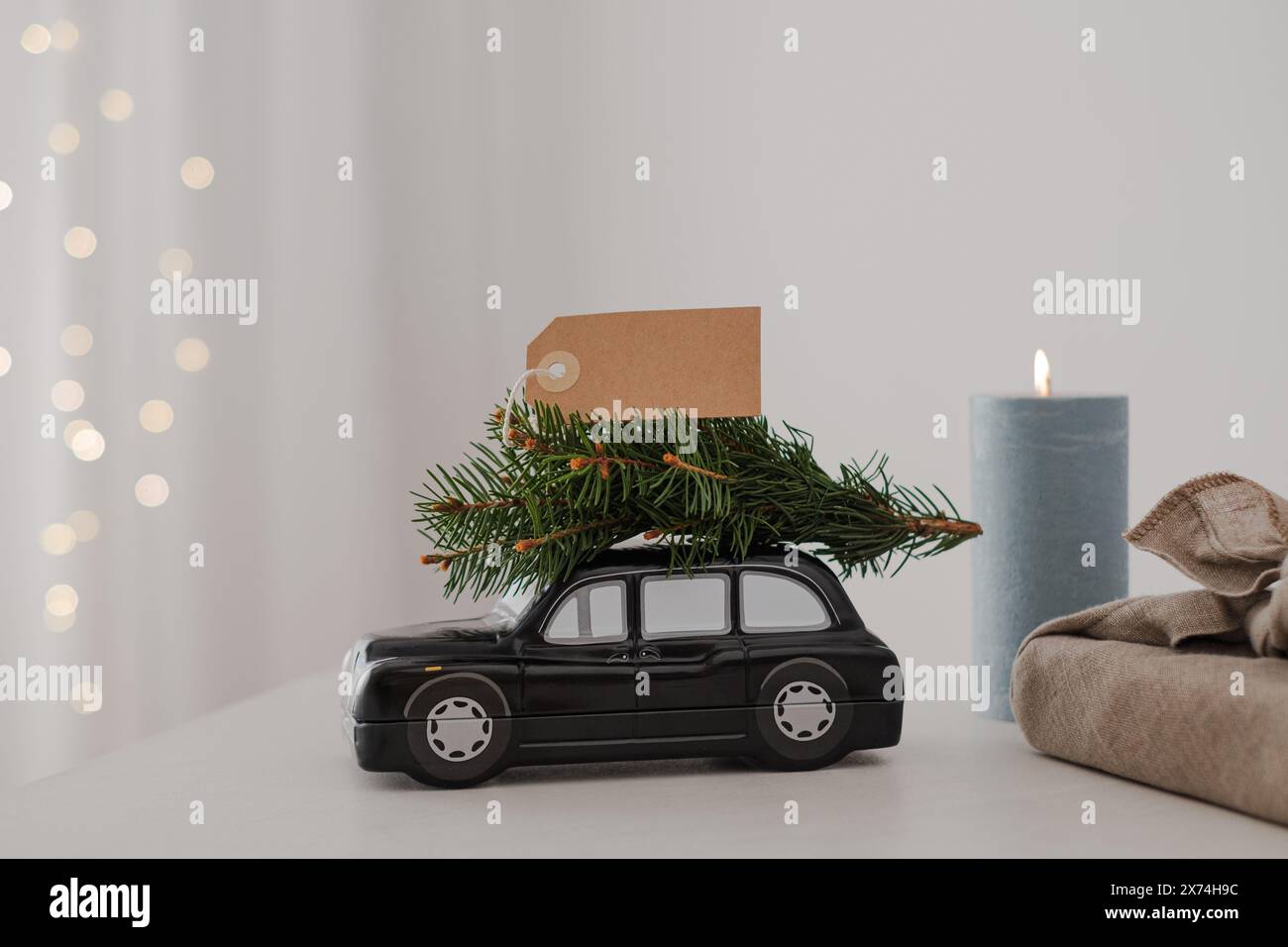 Christmas composition car carries a Christmas tree with blank form tag. on a background of holiday lights Stock Photo