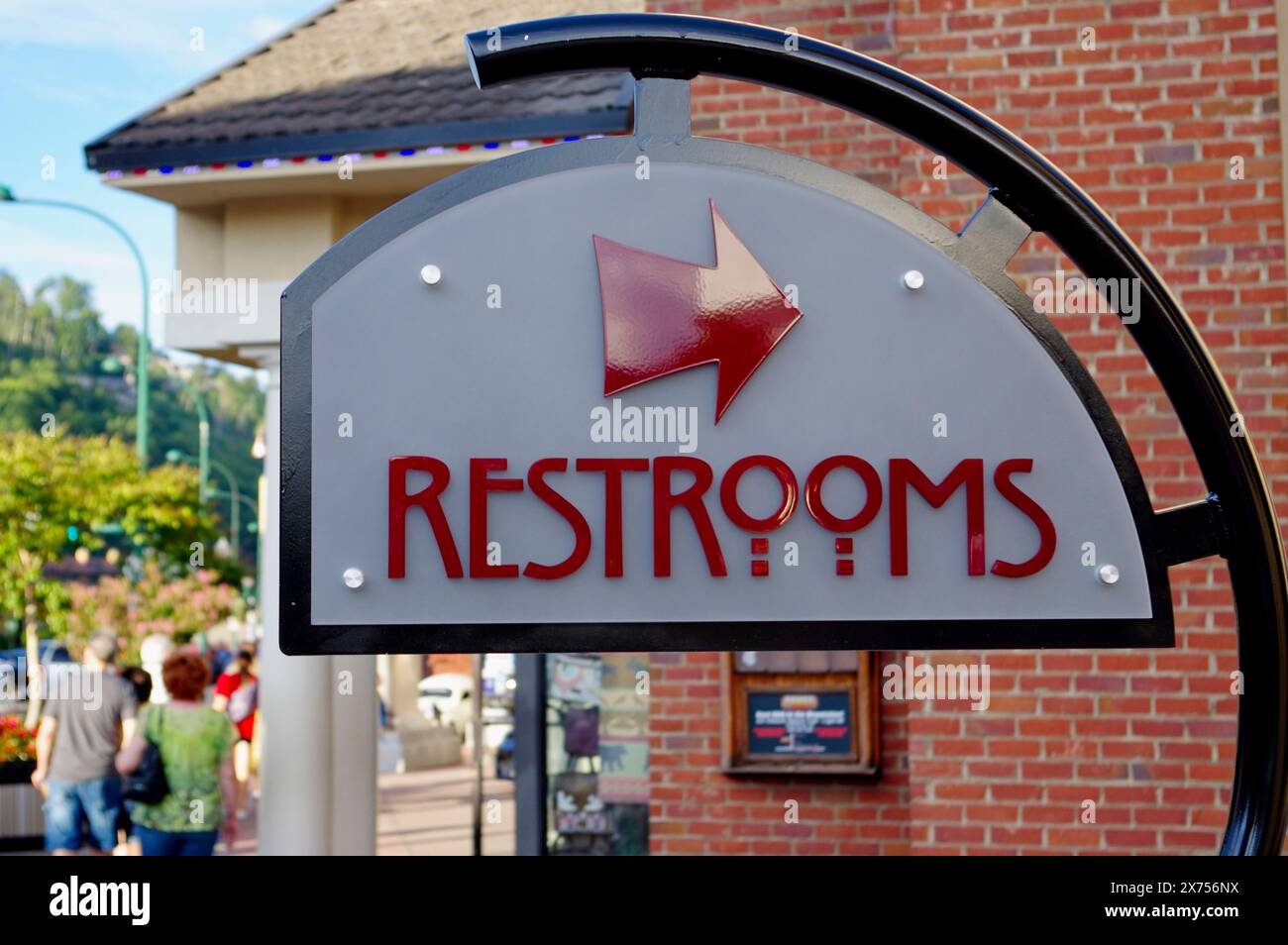 Sign with red letters on a City Sidewalk pointing to restrooms Stock Photo