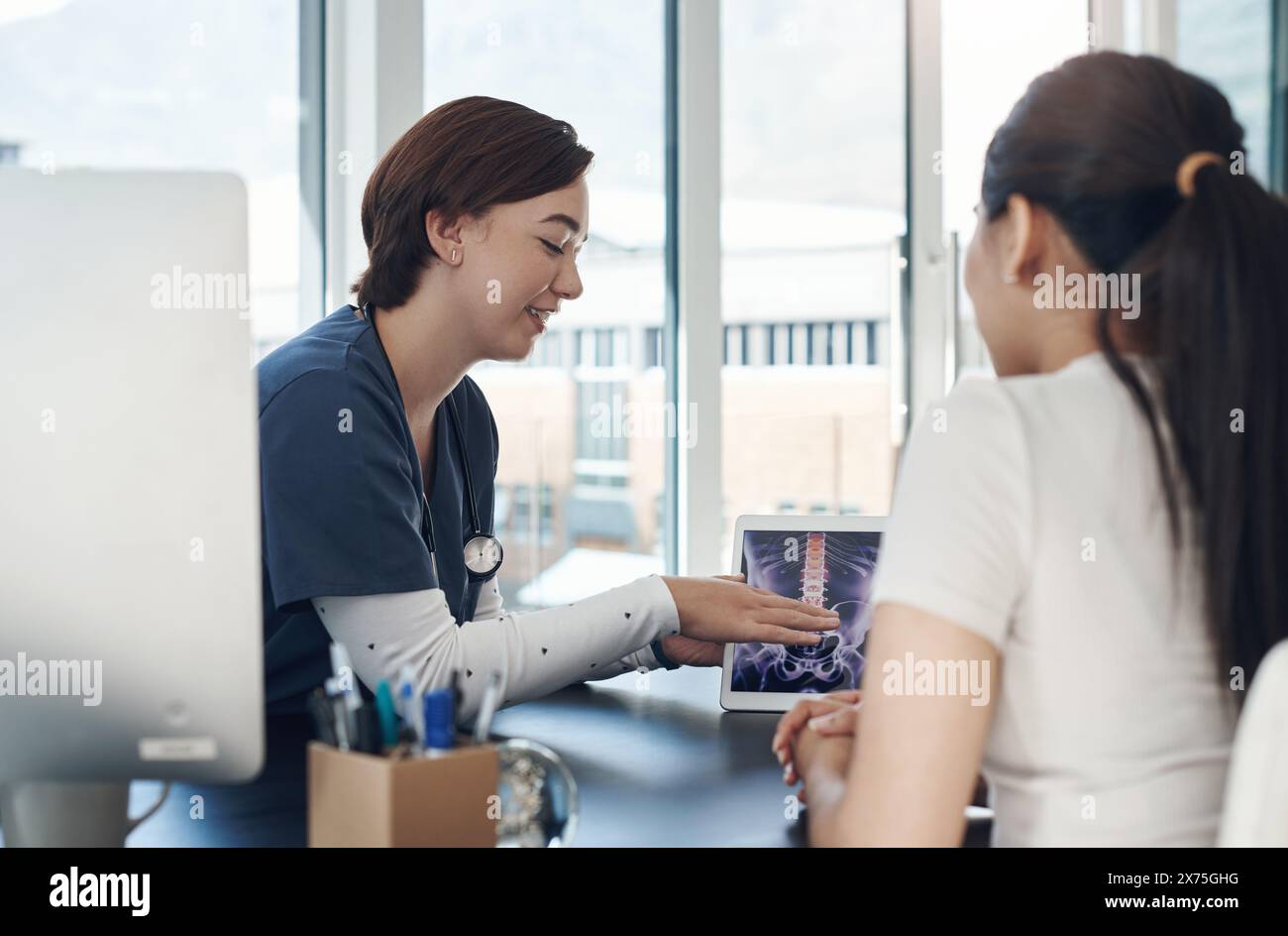 Doctor, woman and tablet for x ray in anatomy, medical or results in MRI, CT and body scan at hospital. Chiropractor, physiotherapy and consulting for Stock Photo