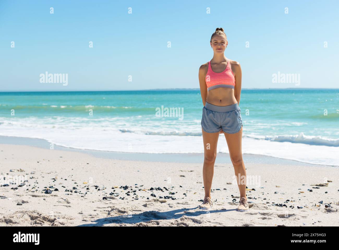 At beach, Caucasian young woman standing, hands on hips Stock Photo