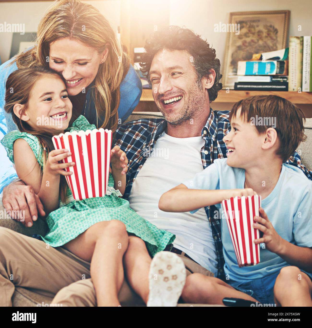 Funny, family and eating popcorn in home living room, laughing and watching movie together on sofa to relax. Parents, kids and food snack for tv, show Stock Photo