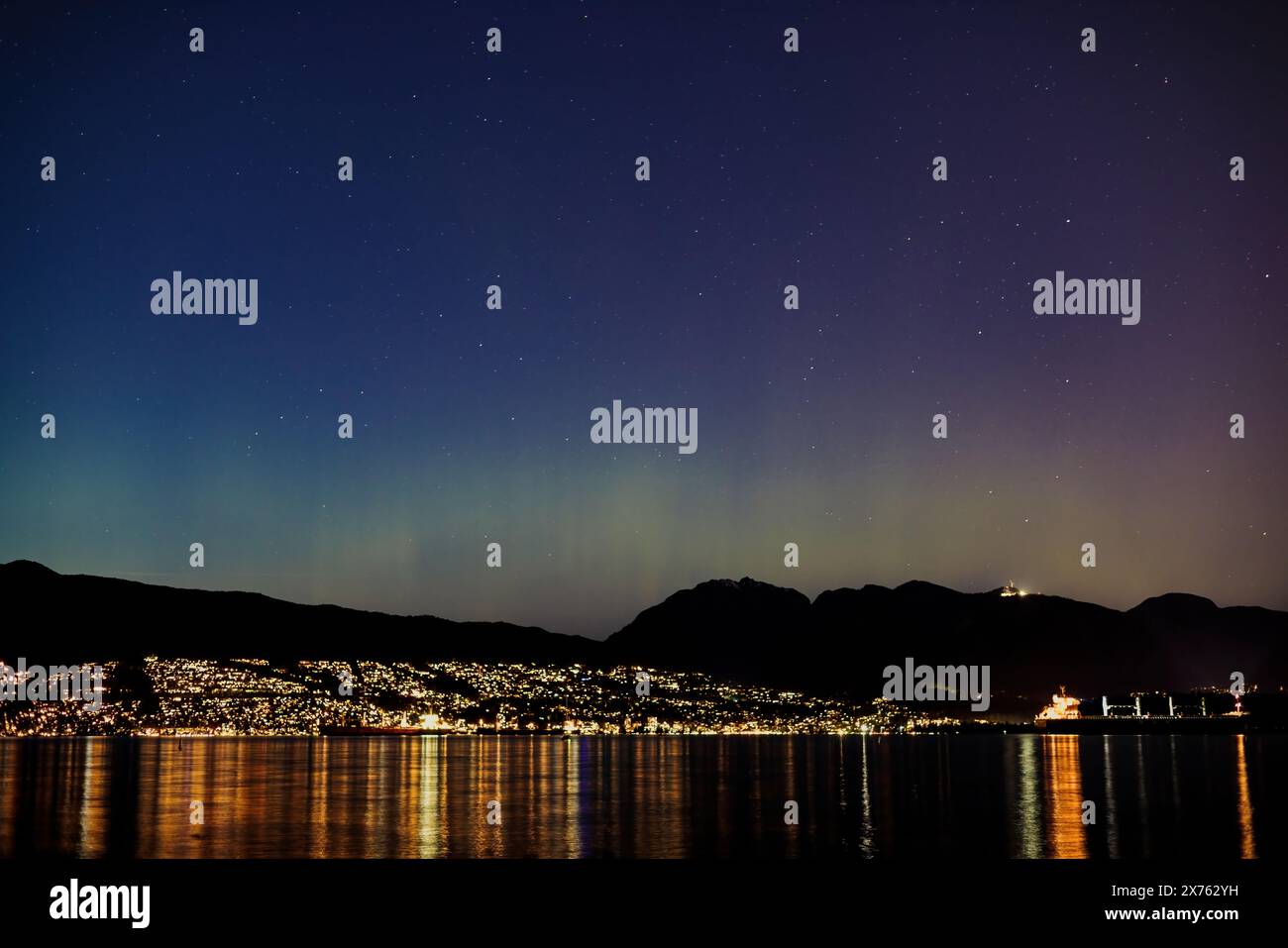Vancouver's North Shore Mountains at night, with lights reflecting on the water. Seen from Jericho Beach in Kitsilano. Stock Photo