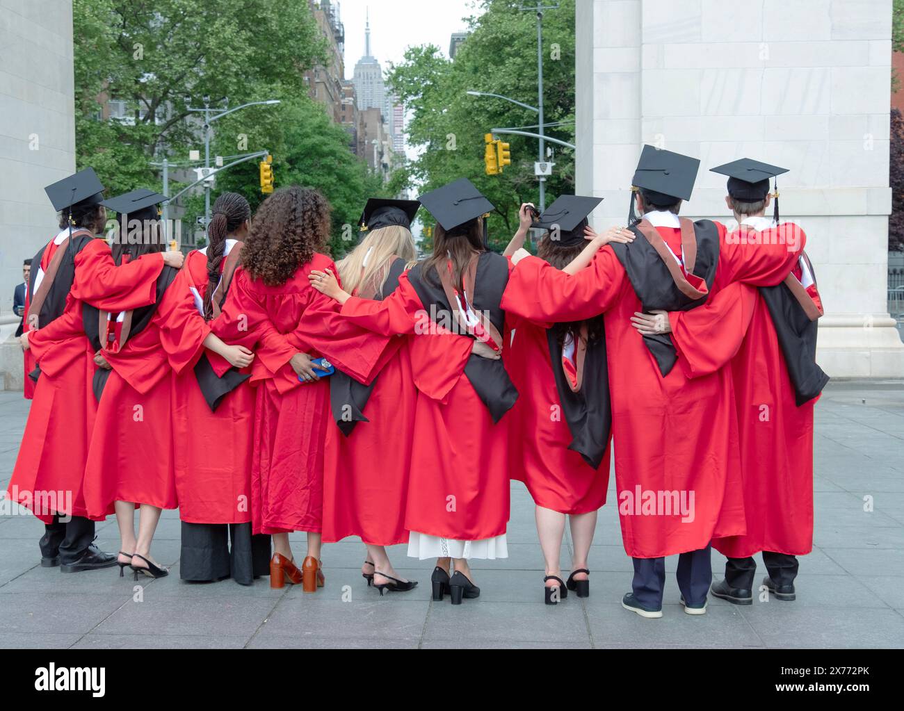 Rear view of graduates from the New School, Parsons School of Design posing in their caps & red gowns near the arch in Washington Square Park in N. Stock Photo