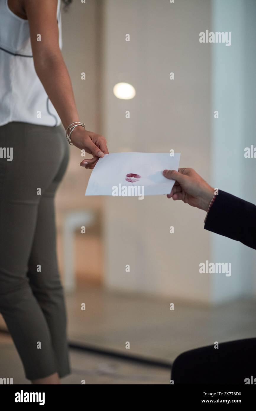 Business people, hands and passing with love letter at office for valentines day, romance or secret admirer. Closeup of employees holding paper with Stock Photo