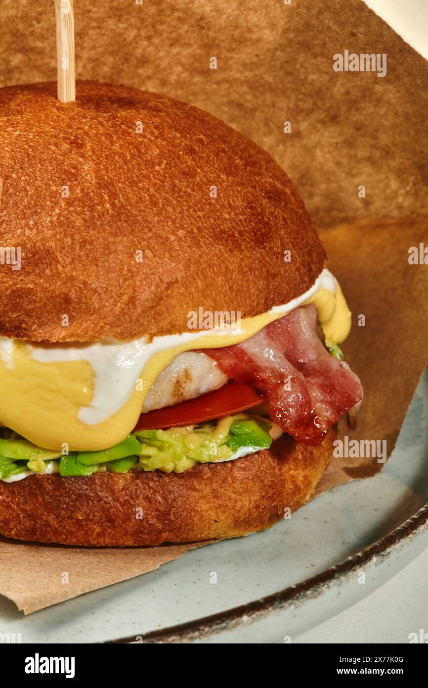 Chicken burger with fried bacon, avocado and cheese sauce Stock Photo