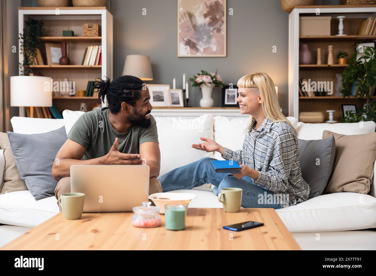 Simple living. Young couple man and woman at home working on laptop, reading book, talking and argue, making fun. Real life situations of two people l Stock Photo