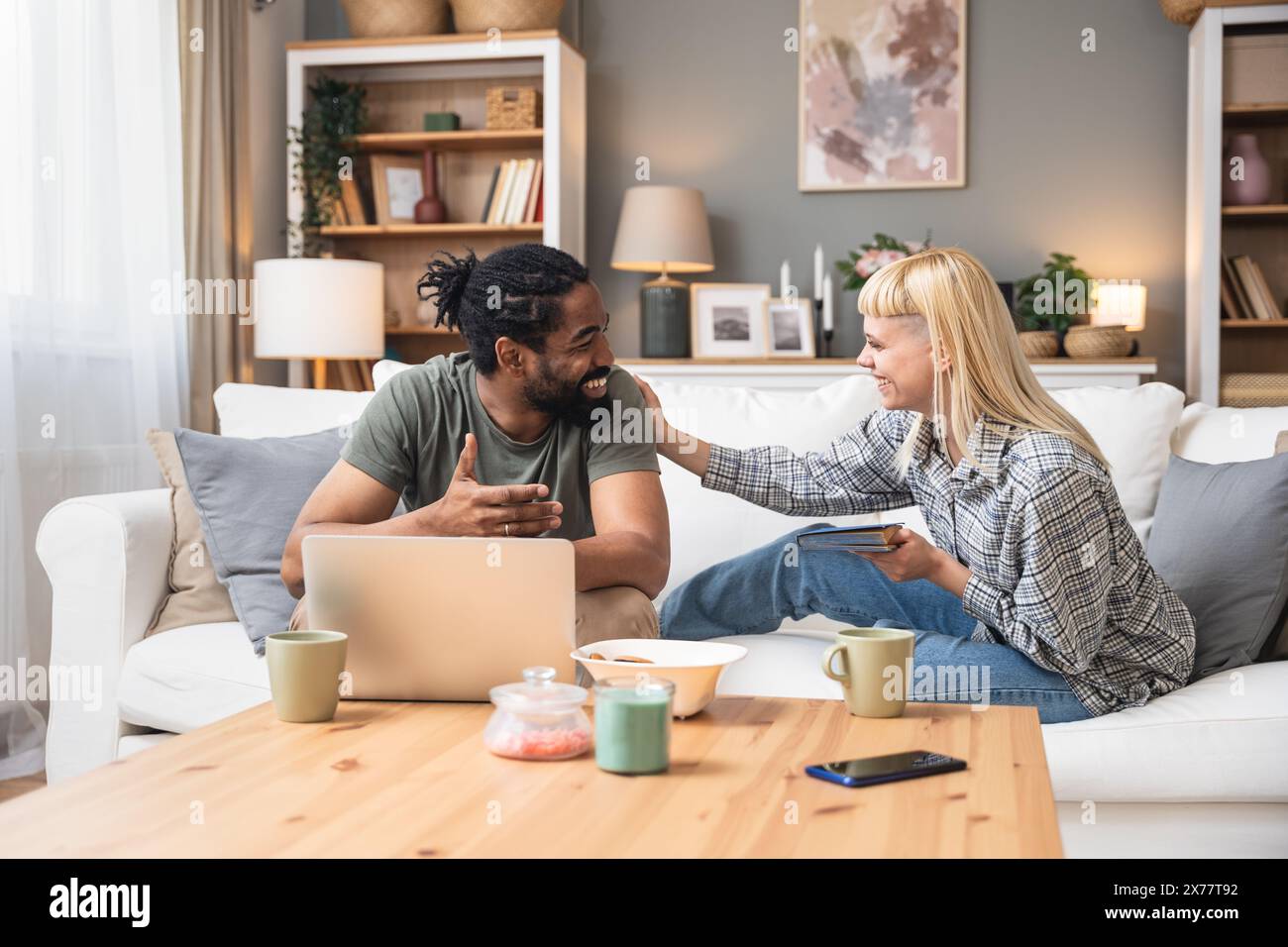 Simple living. Young couple man and woman at home working on laptop, reading book, talking and argue, making fun. Real life situations of two people l Stock Photo
