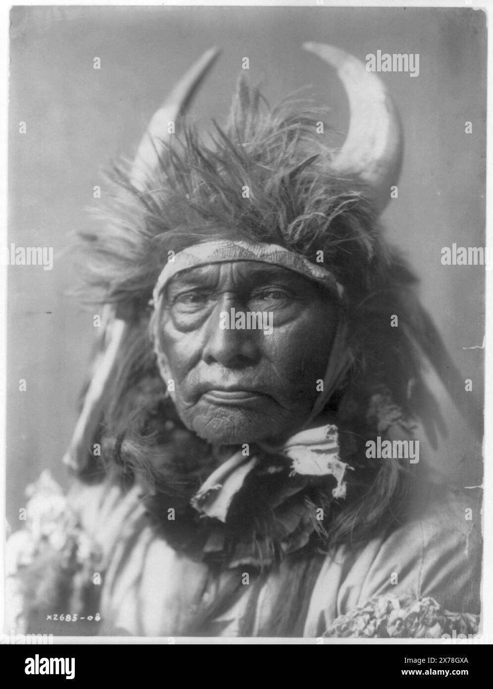 Bull Chief Apsaroke, Curtis no. 2685-08., Forms part of: Edward S. Curtis Collection ., Published in: The North American Indian / Edward S. Curtis. [Seattle, Wash.] : Edward S. Curtis, 1907-30, Suppl., v. 4, pl. 128.. Indians of North America, 1900-1910. , Crow Indians, 1900-1910. , Headdresses, 1900-1910. , Horns (Anatomy), 1900-1910. Stock Photo
