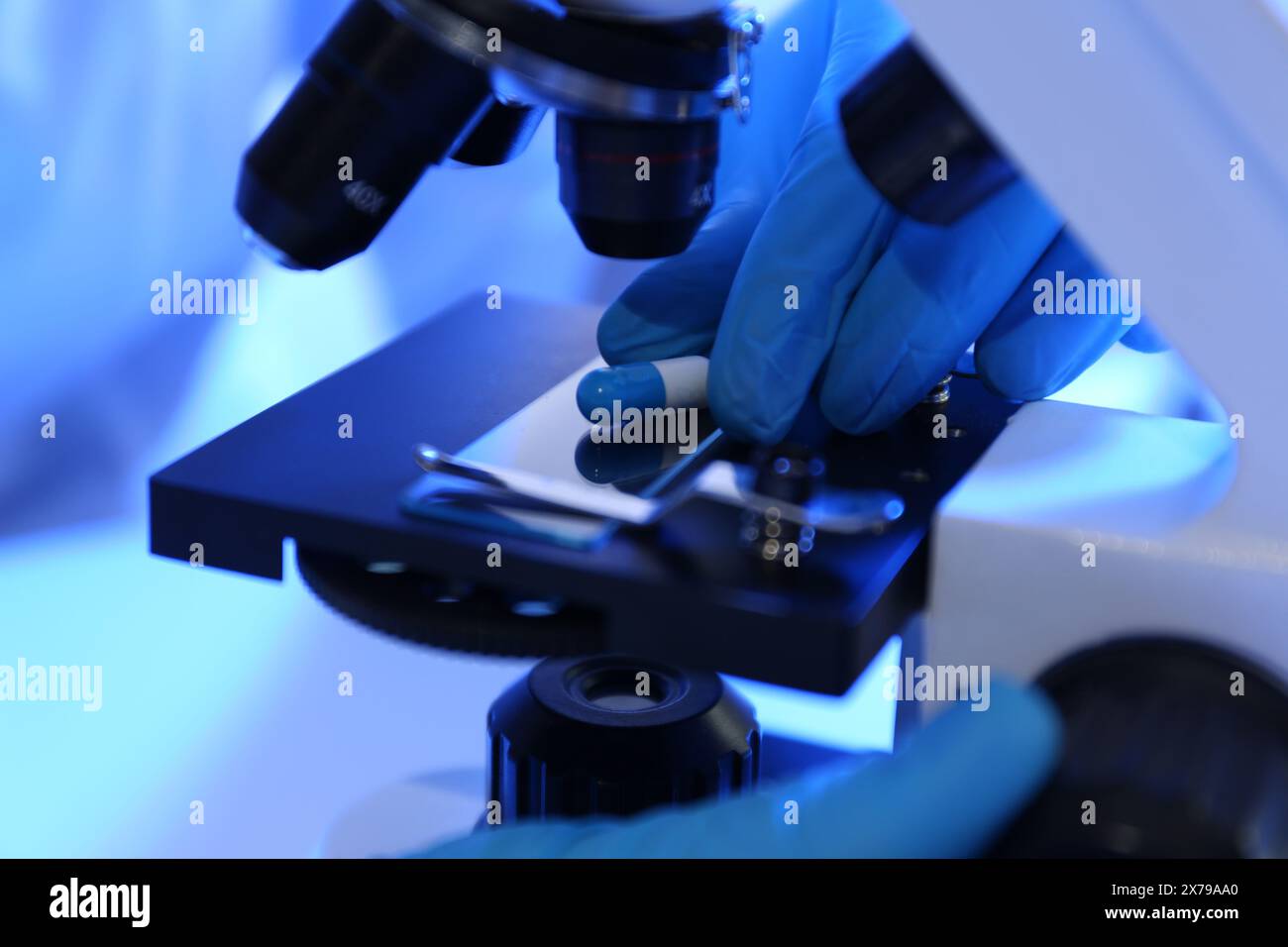 Scientist examining pill under microscope in laboratory, closeup Stock Photo