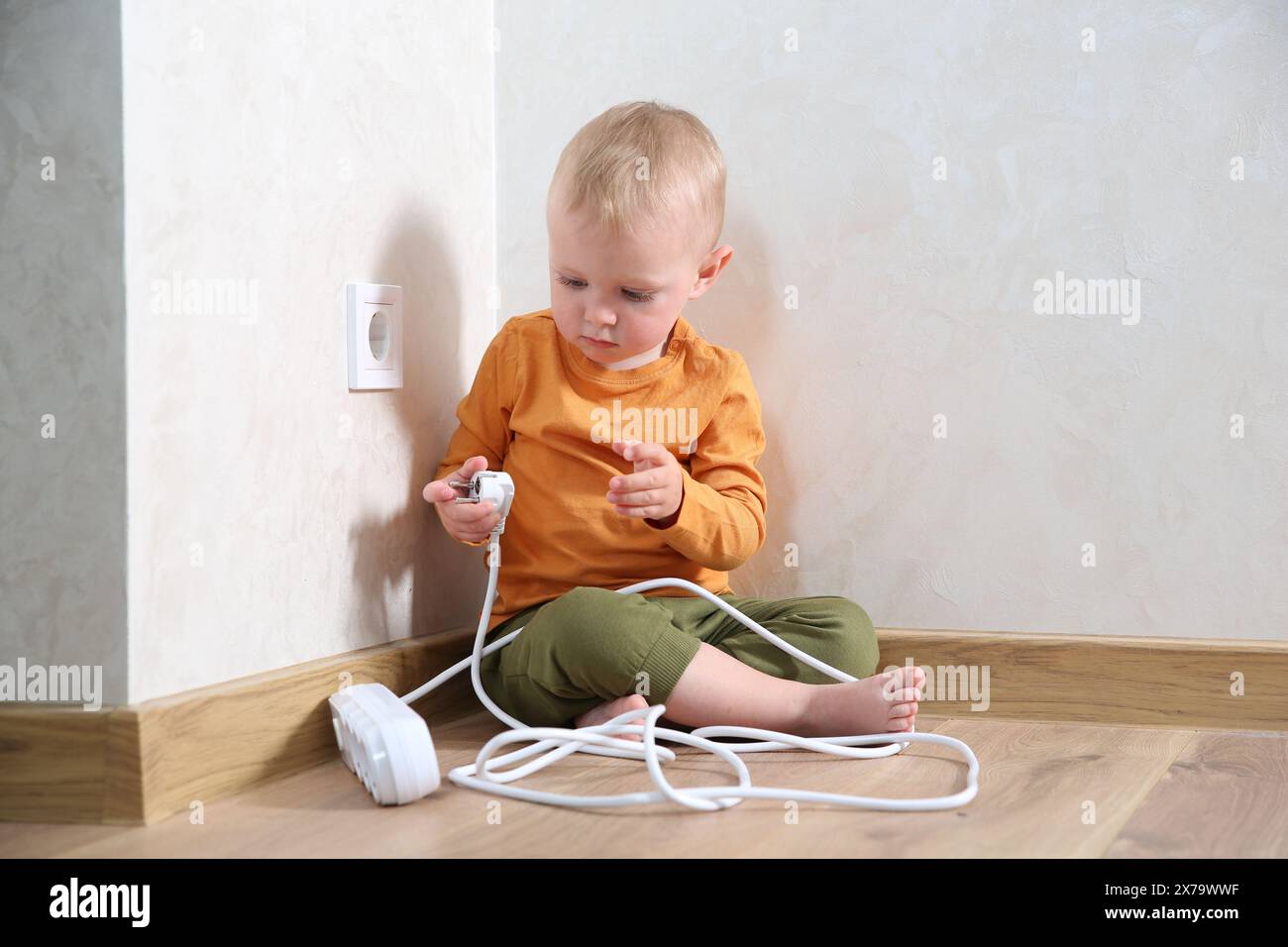 Little child playing with power strip plug near electrical socket at ...