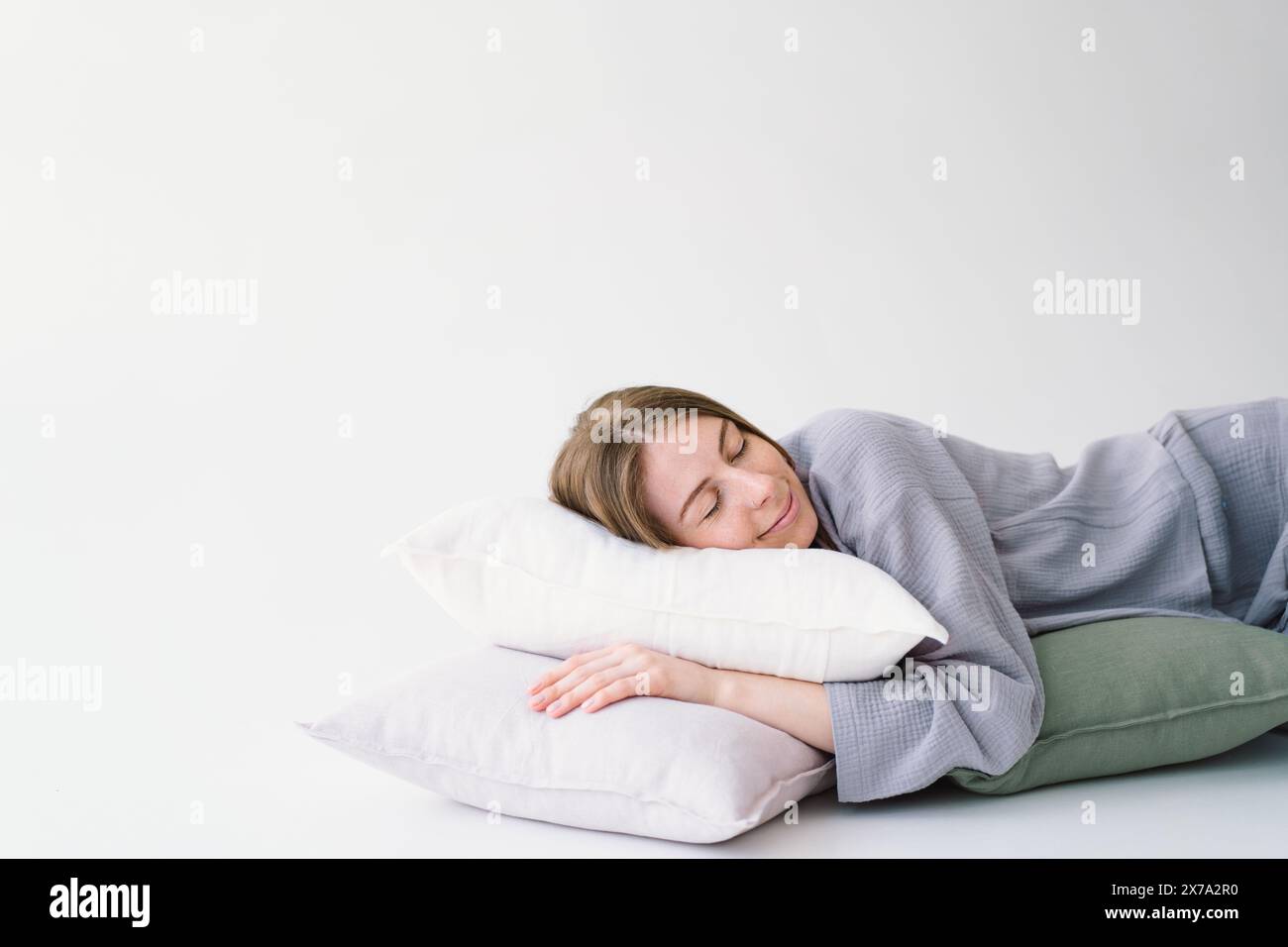 Serene Woman Resting Peacefully With White Pillow on a Light Background Stock Photo