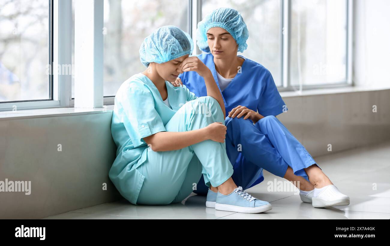 Female doctor calming her stressed colleague in clinic Stock Photo - Alamy
