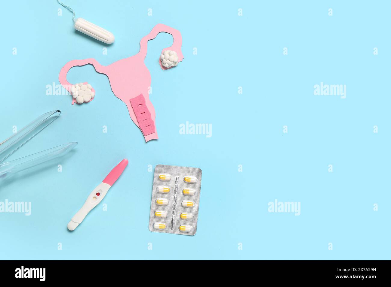 Paper uterus with gynecological speculum, pills, tampon and pregnancy