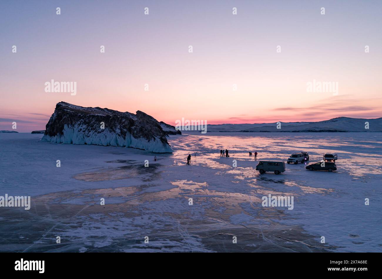Aerial winter landscape of frozen lake Baikal. Groups of tourists got off the cars and walking around the rocky island in lake Baikal, walking on the Stock Photo