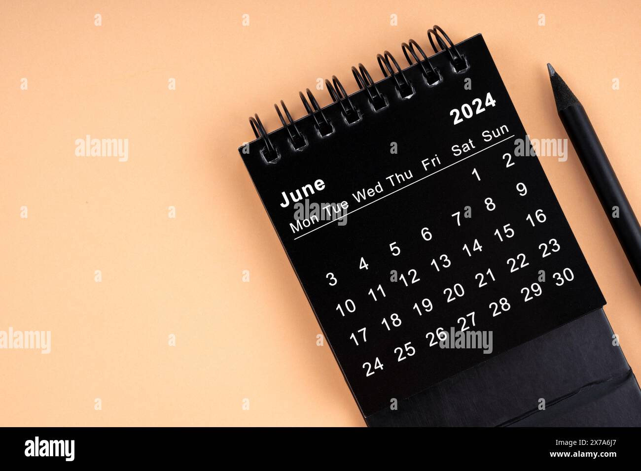 June 2024 Black spiral desktop calendar and wooden pencil on yellow ...