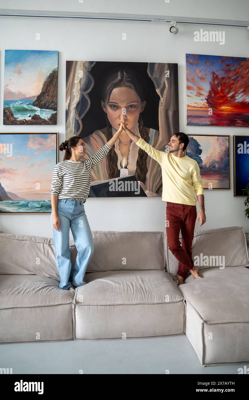Loving creative artist couple delighted with result of decorates walls of home studio with paintings Stock Photo