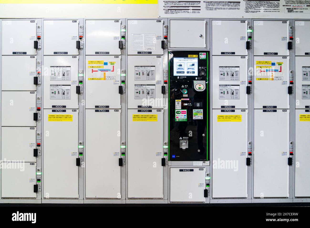 Row of Japanese coin lockers at Akihabara station in Tokyo. Stacked in three sizes priced at 400, 500 and 700 Yen. In middle is a black control panel. Stock Photo