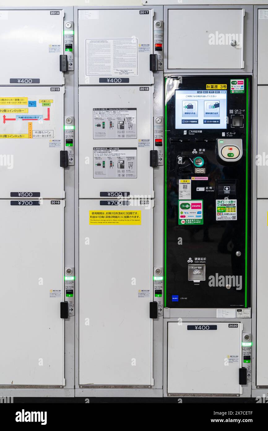 Row of Japanese coin lockers at Akihabara station in Tokyo. Stacked in three sizes priced at 400, 500 and 700 Yen. In middle is a black control panel. Stock Photo