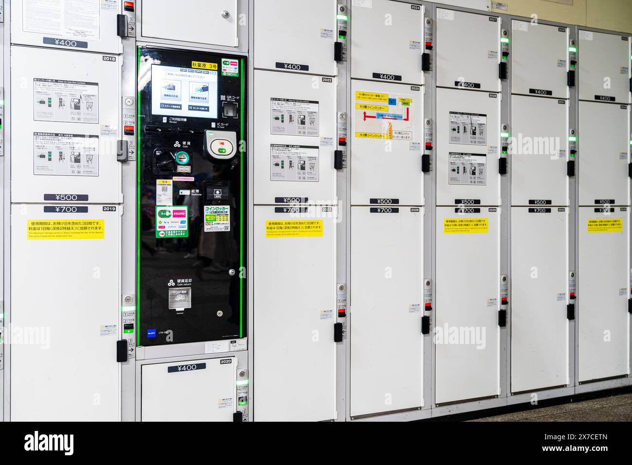 Row of Japanese coin lockers at Akihabara station in Tokyo. Stacked in three sizes priced at 400, 500 and 700 Yen. In middle is a black control panel. Stock Photo