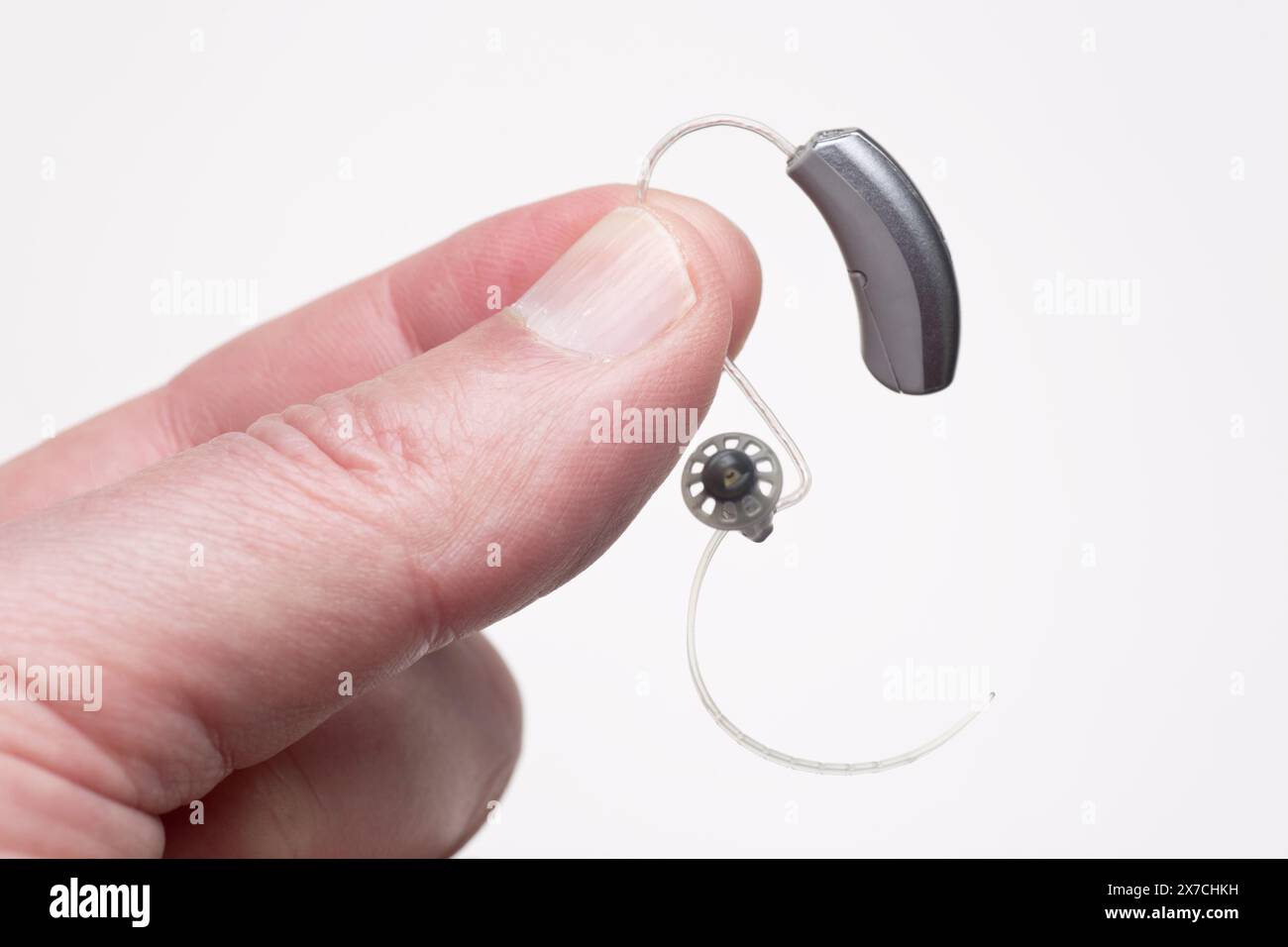 Close-up of showing small discreet hearing aid between fingers Stock Photo