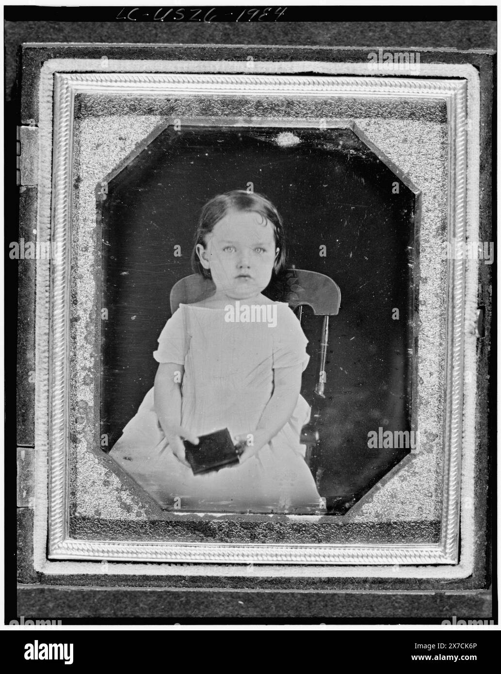 Unidentified girl, three-quarter length portrait, facing front, seated in chair, holding a daguerreotype case, Photographer unidentified., Scratched on back of plate: 1847., Hallmark: Rinhart 46., Case: front, Krainik 187; back, Krainik 198., Accompanying note behind plate: Littlefield, Parsons & Co. Manufacturers of Daguerreotype Cases. L., P. & Co., are the sole proprietors and only legal manufacturers of UNION CASES, WITH THE Embracing Riveted Hinge. Patented, Oct. 14, 1856 & April 21, 1857., Source unknown., Forms part of: Daguerreotype collection ,  Exhibited: When they were young. Librar Stock Photo