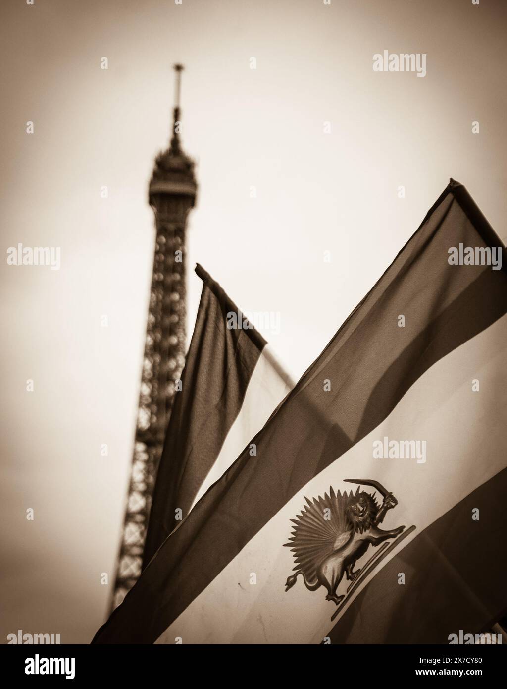 Old Iranian flag (Iran's flag under the former Shah regime) and Eiffel tower at background. Demonstration in Paris, France. Sepia historic photo. Stock Photo