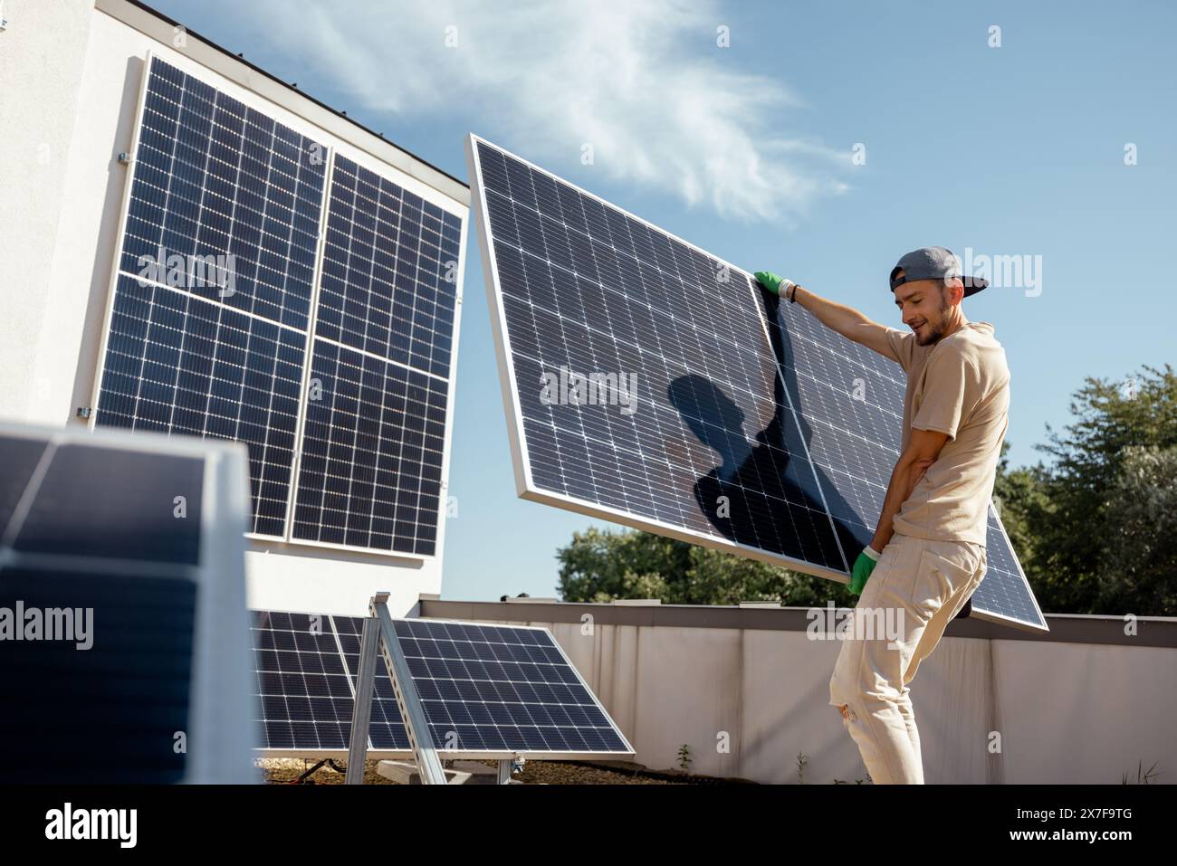 Man installing solar panels on a rooftop Stock Photo