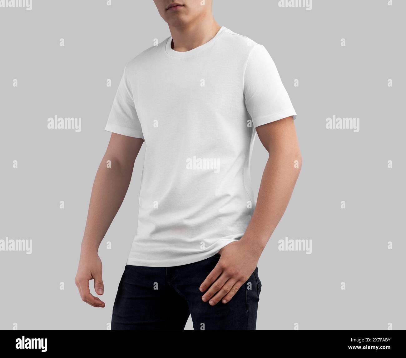 White t-shirt template on sporty guy in dark jeans, men's crew-neck shirt, front view, isolated on studio background. Blank streetwear, male clothes m Stock Photo