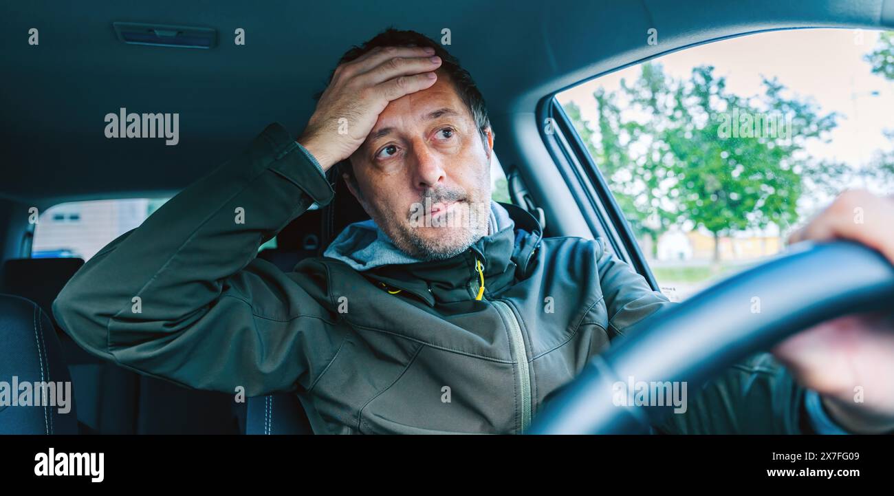 Troubled car driver covering his face with hand after traffic accident, selective focus Stock Photo